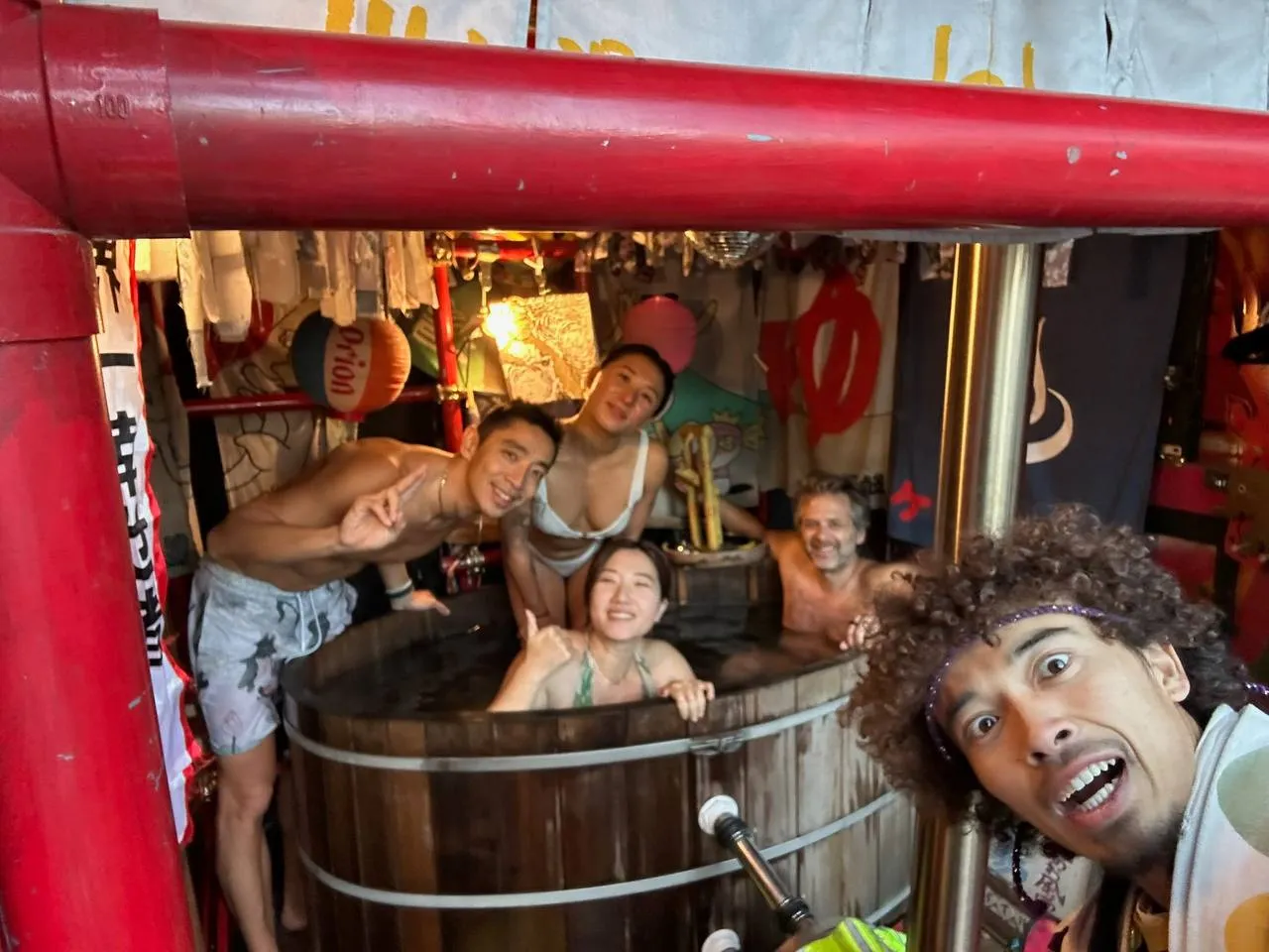 Inside the mobile sento — wood-burning stove, disco ball, and Kerorin bath buckets