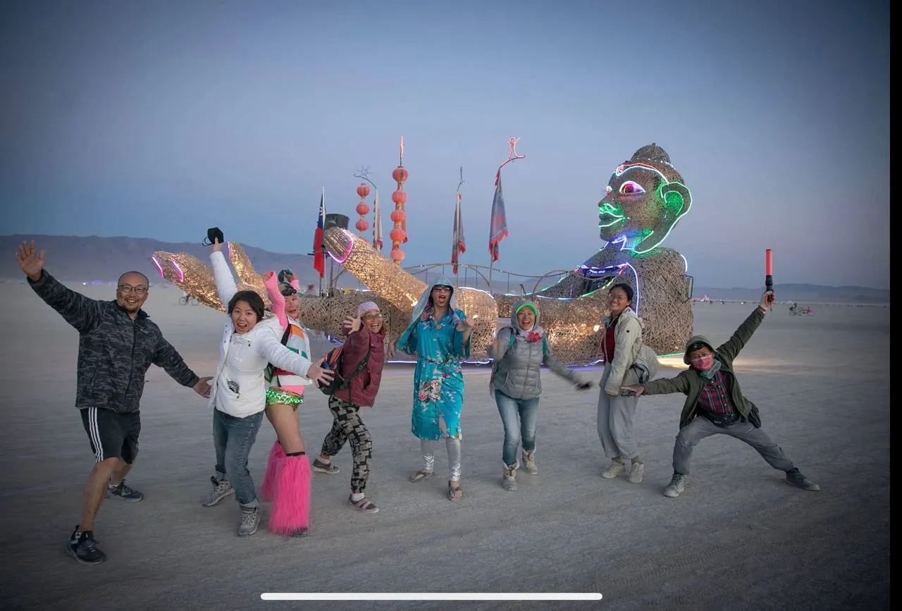 Zulai on the playa at dusk — the team poses in front of the illuminated sculpture